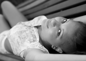 chica tumbada en banco, mirando a cámara