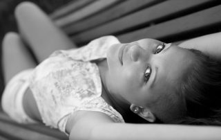 chica tumbada en banco, mirando a cámara