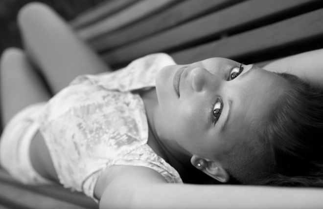 chica tumbada en banco, mirando a c&aacute;mara